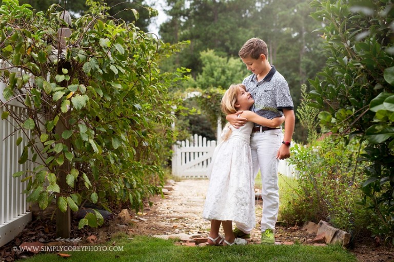 outdoor portrait of siblings by a white picket gate by Atlanta photographer, Simply Corey Photography