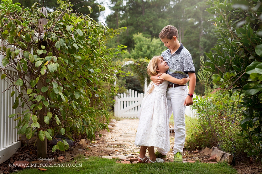siblings by a white picket fence by Atlanta family lifestyle photographer, Simply Corey Photography