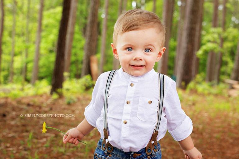 Douglasville baby photographer, one year old boy in suspenders holding a flower