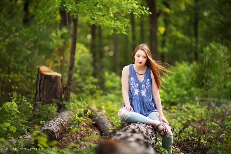 teen outside on a log in the woods by Atlanta senior portrait photographer