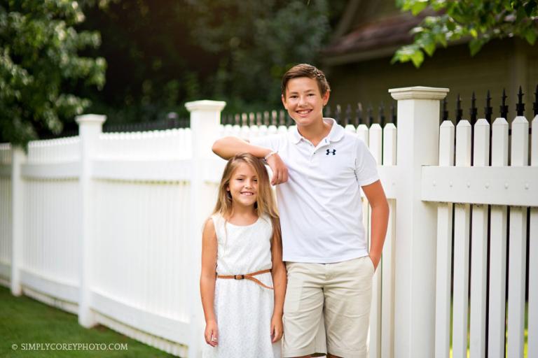 brother and sister near a white fence by Carrollton family photographer