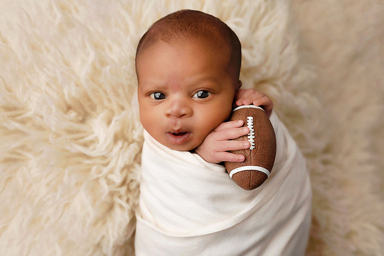 newborn photographer near Douglasville, awake baby boy holding a football