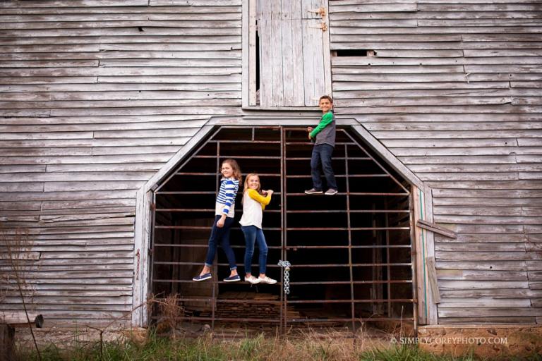 Carrollton family photographer, children climbing on a big barn gate