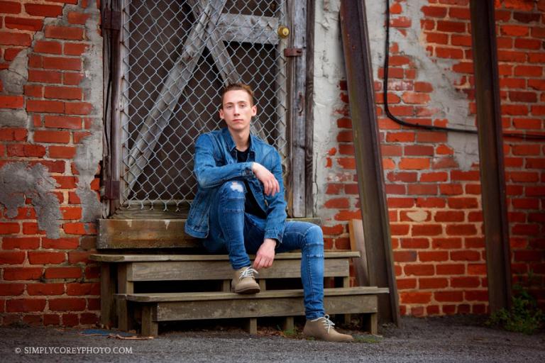Douglasville senior portraits, teen boy in a jean jacket by a brick wall