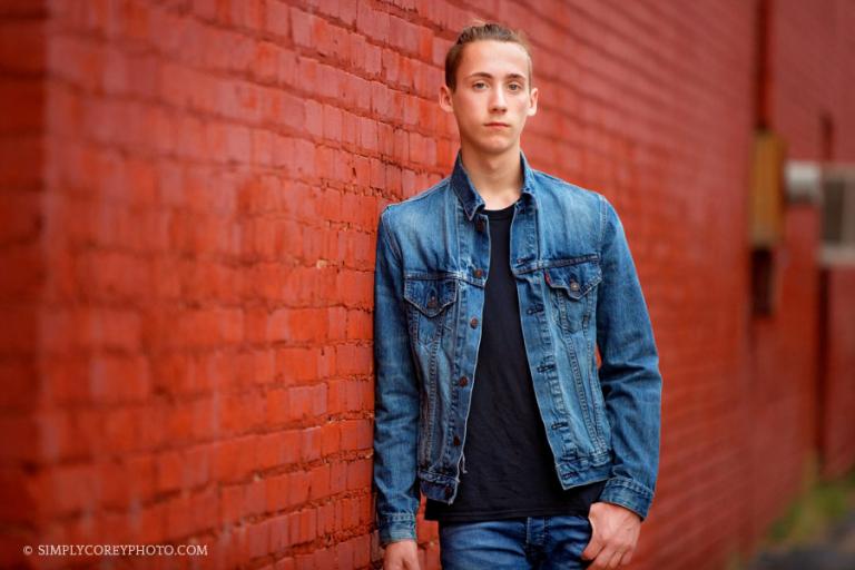 Villa Rica senior portraits, teen boy in a denim jacket near a brick wall