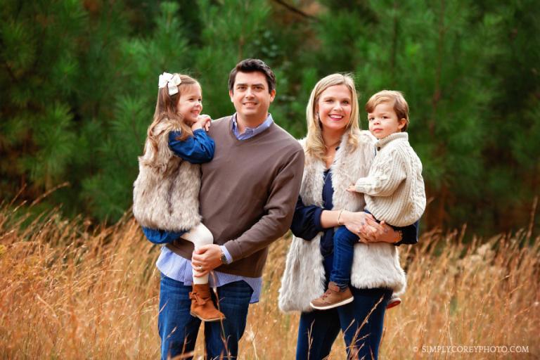 Newnan family photographer, parents holding kids in front of pine trees