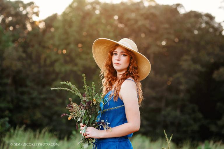 Douglasville senior photographer, teen outside in a floppy hat with flowers