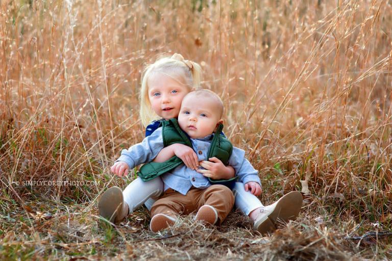 Newnan family photographer, sister holding baby brother in tall golden grass