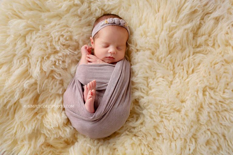 newborn photographer Carrollton, Georgia; baby in a purple wrap on a flokati