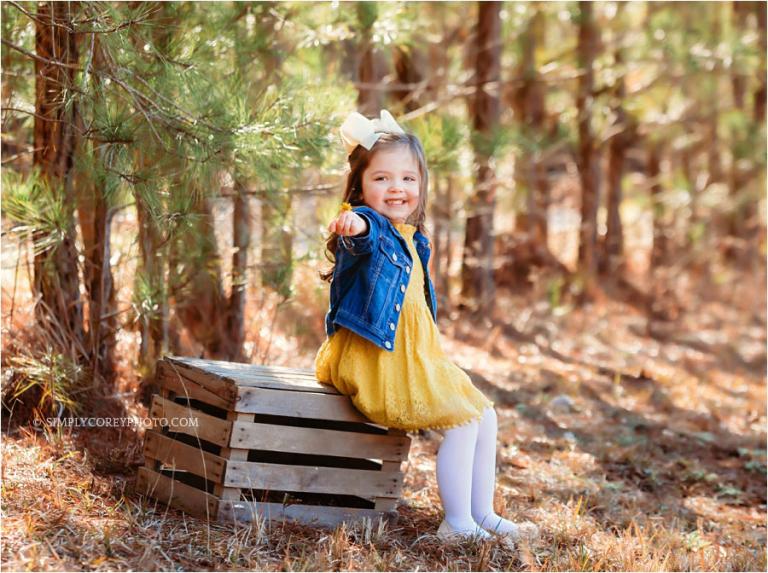 Carrollton child photographer, girl outside near pine trees