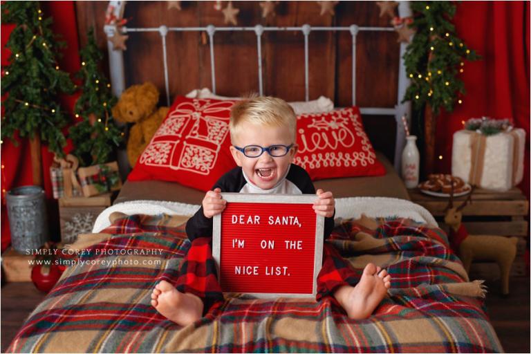 Atlanta Christmas pajama mini sessions, boy in glasses holding a sign