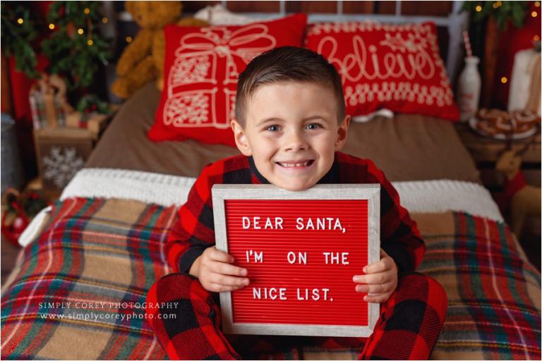Carrollton Christmas mini sessions, kid in pajamas with nice list sign