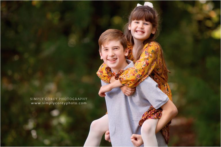 Villa Rica family photographer, kids piggy back ride outside
