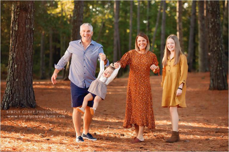 Bremen family photographer, parents swinging toddler outside