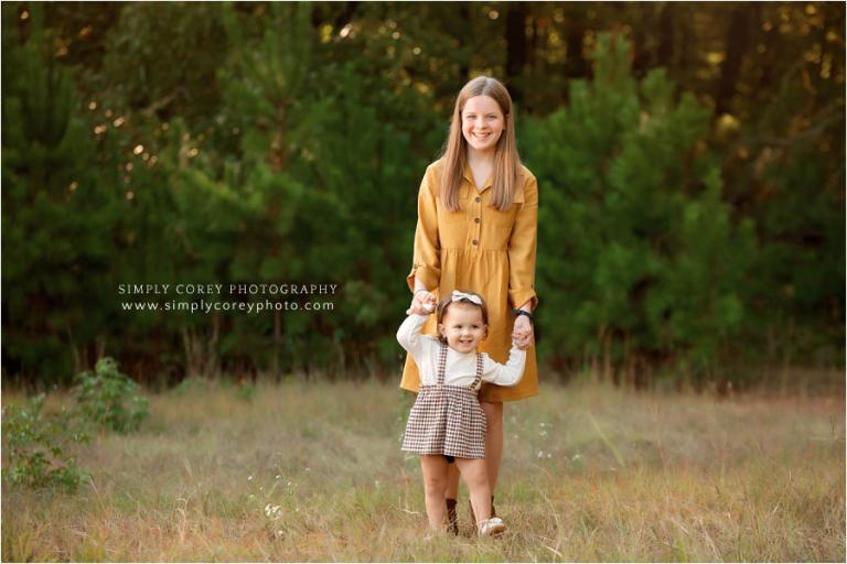 Douglasville family photographer, tween with baby sister outside in a field