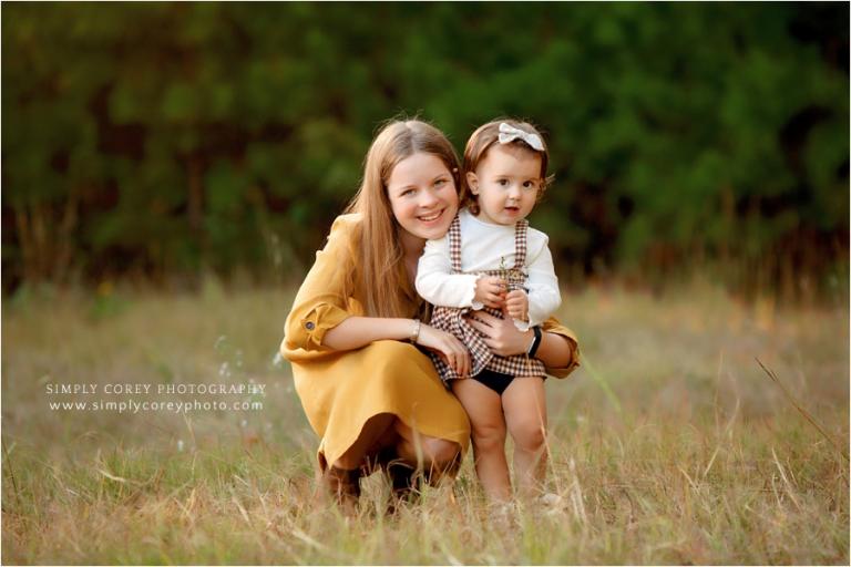 family photographer near Atlanta, tween with baby sister in a field