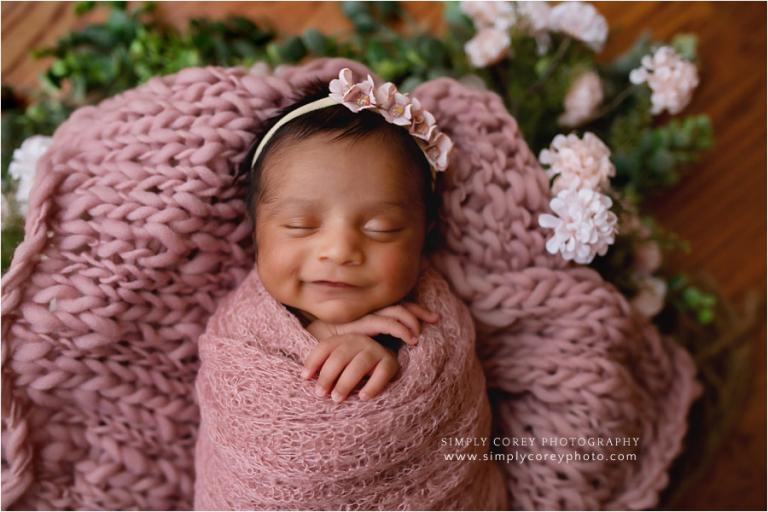 Atlanta newborn photographer, baby smiling with pink flowers