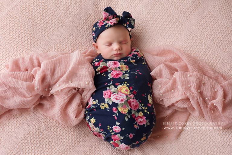 Carrollton newborn photographer, baby in navy rose swaddle on pink