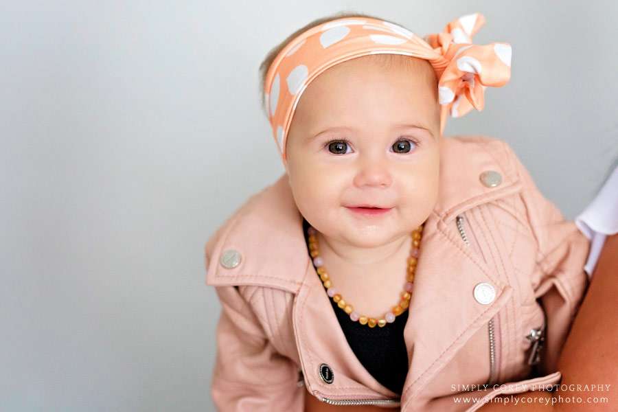 Carrollton baby photographer, mom holding baby wearing a pink leather jacket