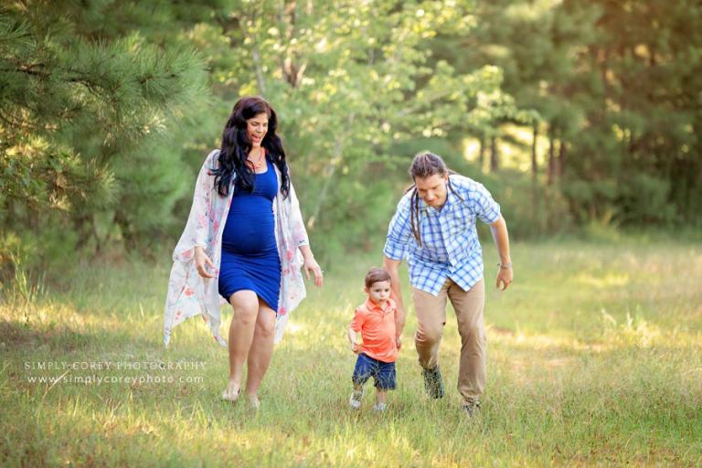 Peachtree City family photographer, parents chasing toddler during outdoor maternity session