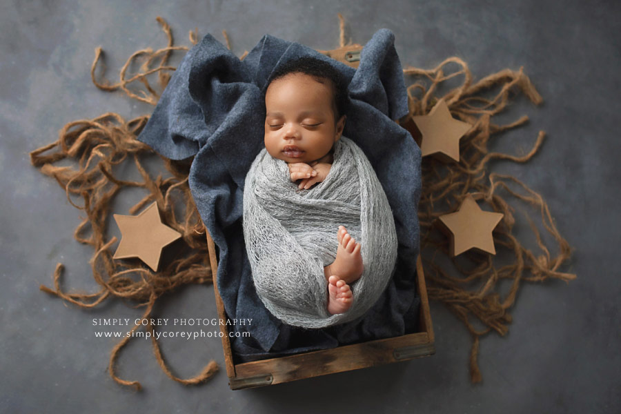 newborn photographer near Atlanta, baby boy wrapped in a crate with stars and jute