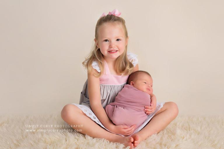 newborn photographer near Douglasville; big sister holding baby girl
