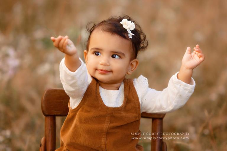 Atlanta baby photographer, toddler outside in field holding flowers