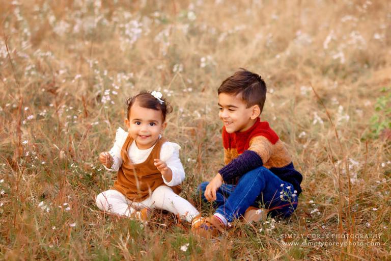 Carrollton family photographer, siblings sitting outside in field in fall