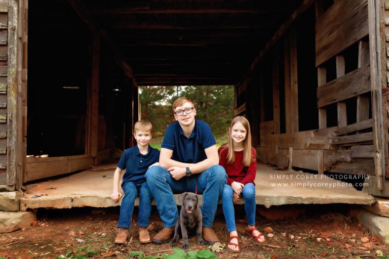 Carrollton family photographer in Georgia; kids in old barn with puppy