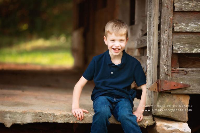 kids photographer near Hiram, child outside sitting in old barn