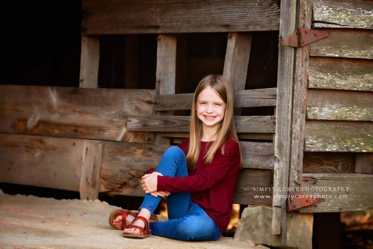 Villa Rica children's photographer, child sitting outside in old barn