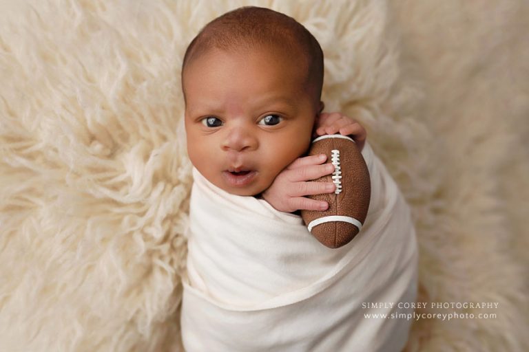 newborn photographer near Peachtree City, awake baby boy holding football