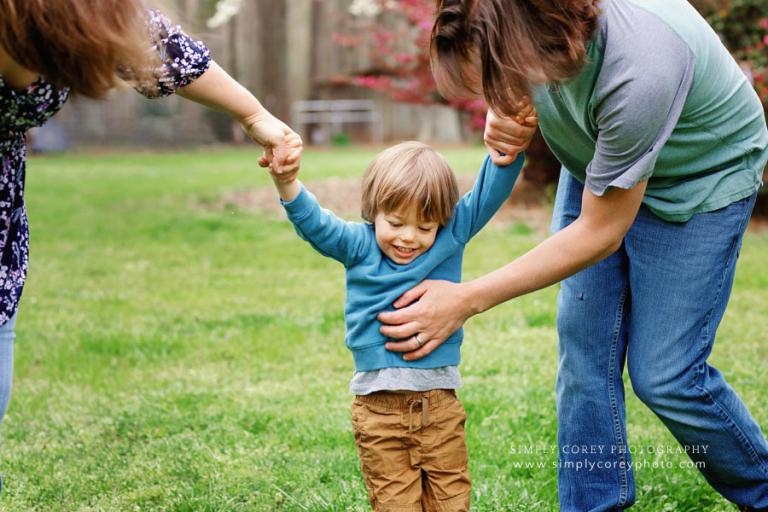 Douglasville family photographer candid of dad tickling son outside