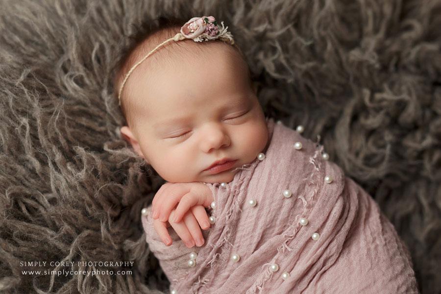 Villa Rica newborn photographer, baby girl in pink pearl swaddle on brown flokati