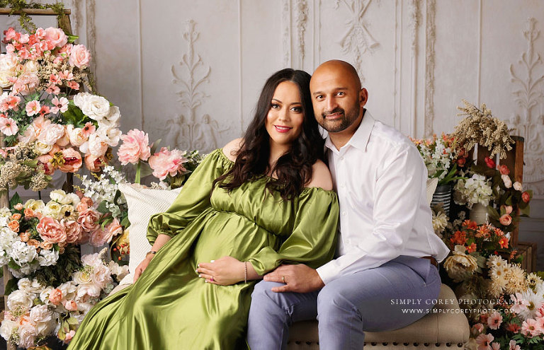 Atlanta maternity photographer, expecting couple sitting in studio with flowers