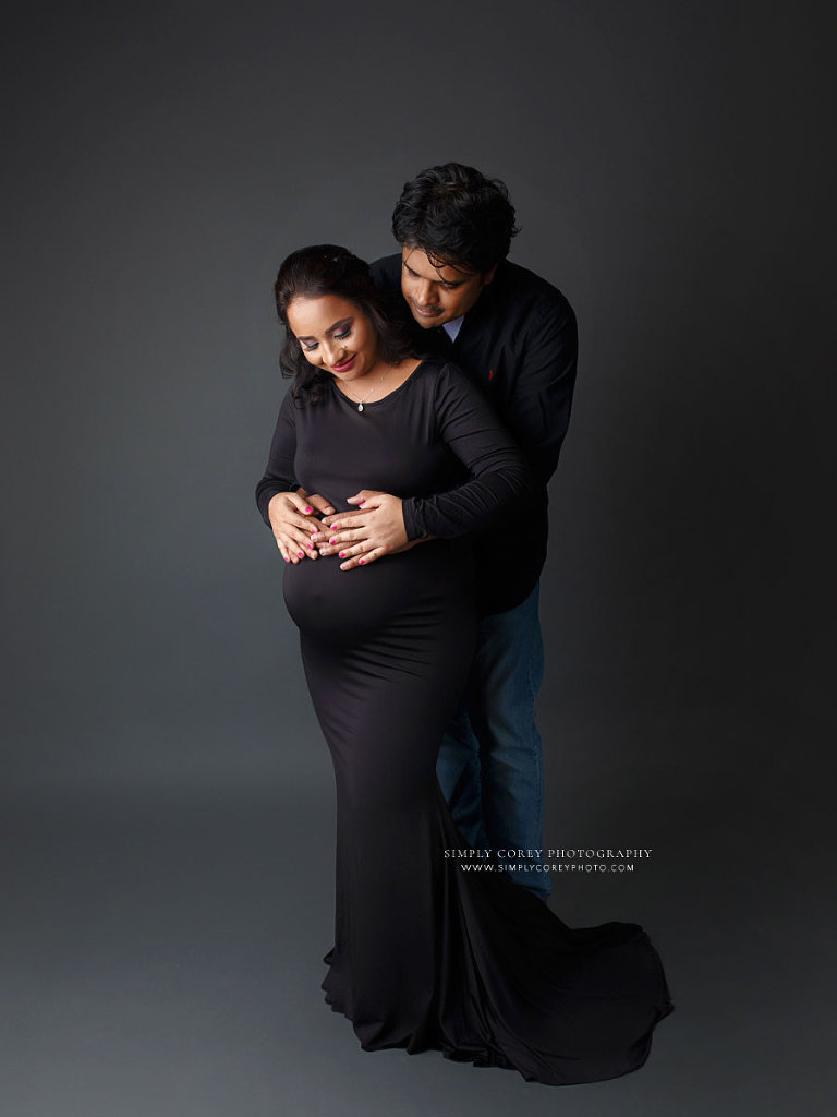 Newnan maternity photographer, expecting couple wearing black with grey studio backdrop