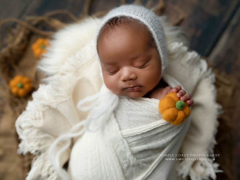 newborn photographer near Atlanta, baby boy in white set with little pumpkins