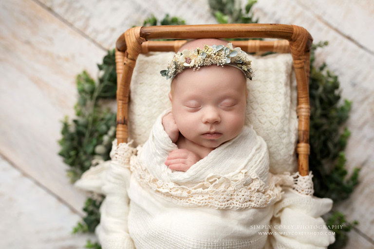 newborn photographer near Atlanta, baby girl in rattan bed with ivory wrap and flower crown