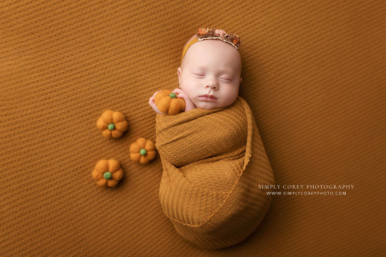newborn photographer near Villa Rica, baby girl in mustard wrap set with pumpkins