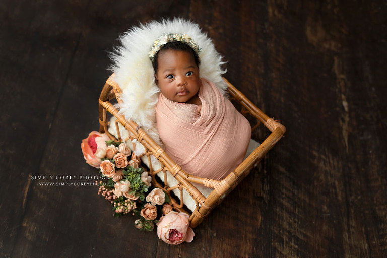 newnan newborn photographer, awake baby girl in pink swaddle and rattan bed with flowers