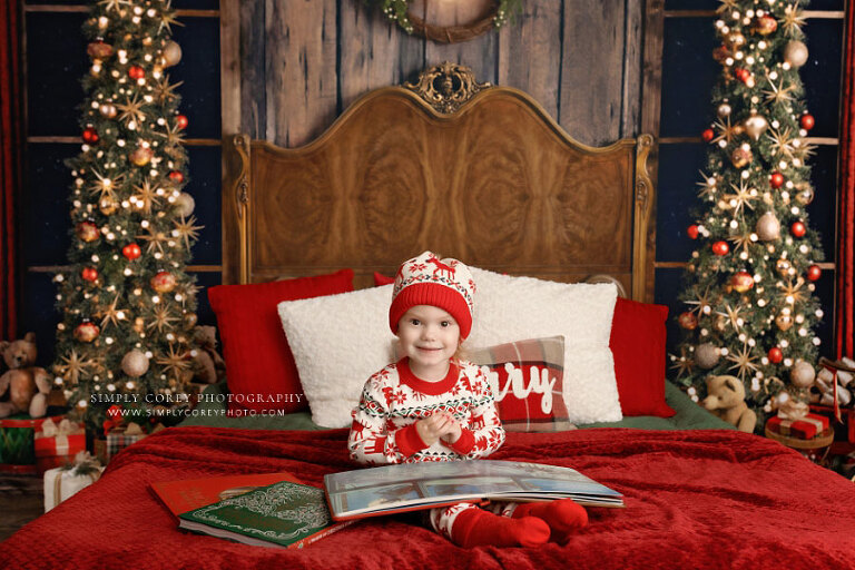 Bremen mini session photographer, child in Christmas pajamas with books on a bed in studio