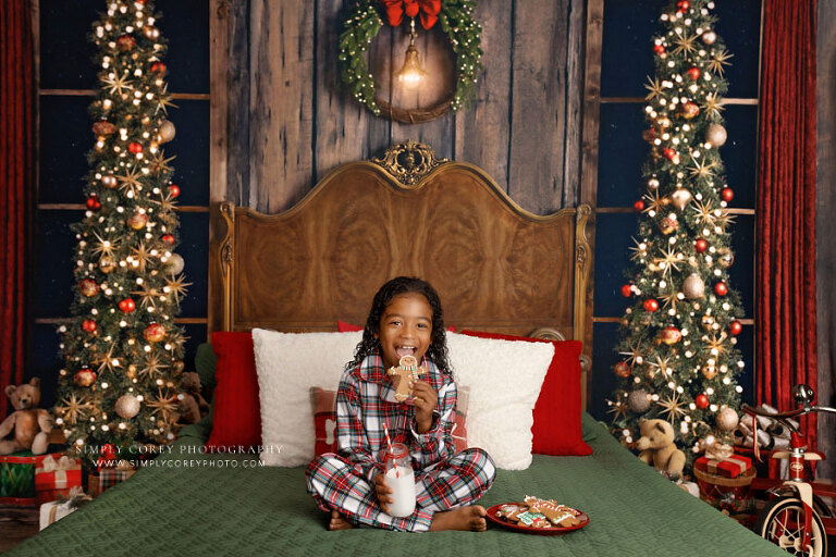 Douglasville mini session photographer, child in Christmas pajamas on bed with milk and cookies