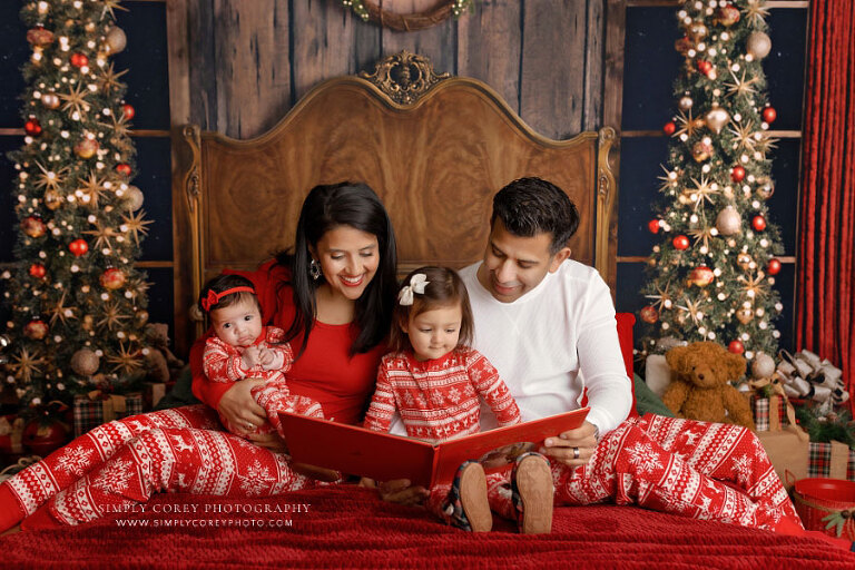mini session photographer near Atlanta, family reading book on bed in Christmas pajamas