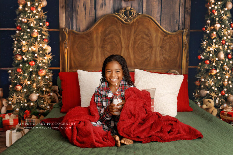 mini session photographer near Fairburn, child in Christmas pajamas wrapped in blanket