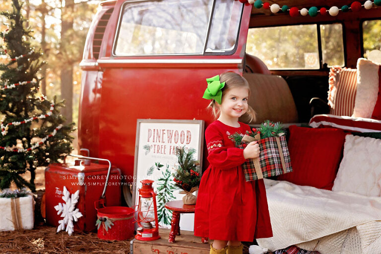 Atlanta mini session photographer, child with present in outdoor Christmas set with VW Bus