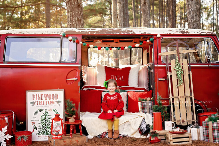 mini session photographer near Newnan, child in red dress on Christmas VW Bus set