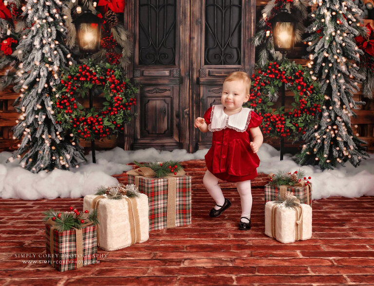 Christmas mini session photographer near Carrollton, GA, baby walking through presents