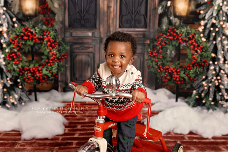 Douglasville baby photographer, boy smiling on tricycle for Christmas mini session
