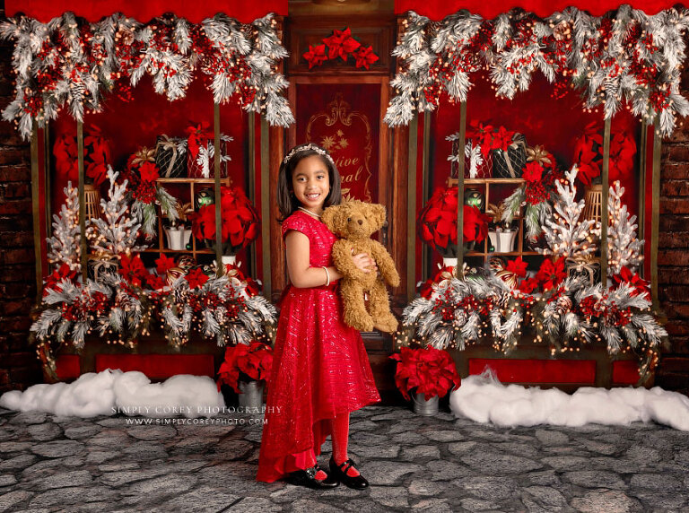 Hiram mini session photographer, child in red dress with teddy bear on poinsettia set