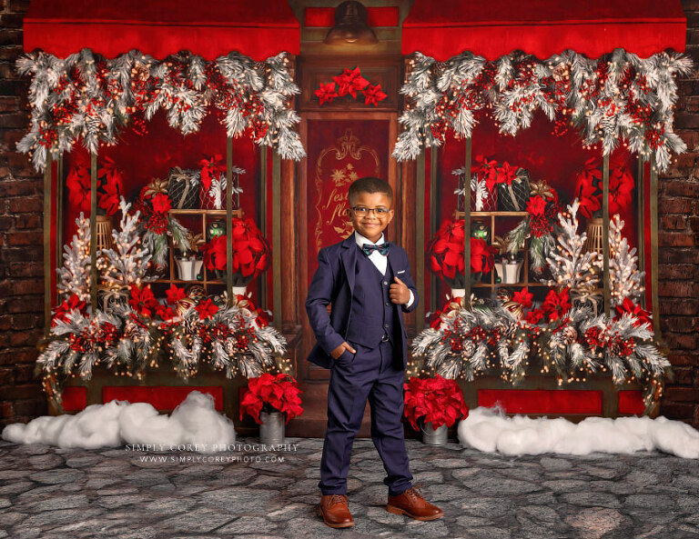 mini session photographer near Atlanta, child in suit on Christmas studio set with poinsettias